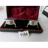 A cased pair of silver salts with blue glass liners