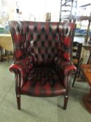 A deep button back maroon leather library wing back chair