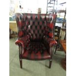 A deep button back maroon leather library wing back chair