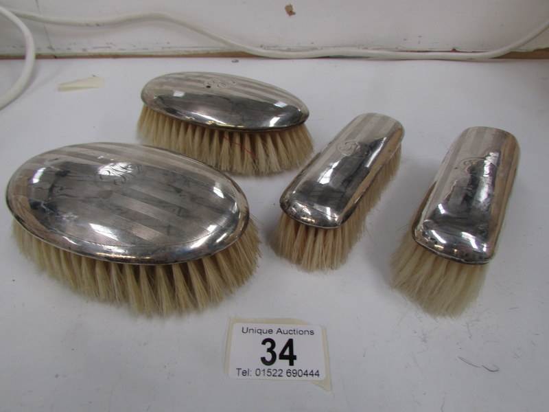 4 matching silver backed brushes