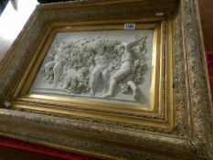 A gilt framed marble plaque with cherub scene and medallion to rear