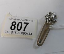 A silver bookmark surmounted frog