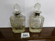 A pair of etched crystal perfume bottles with silver tops