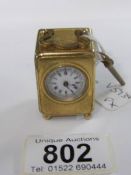 A miniature French brass carriage clock with enamel dial and complete with key