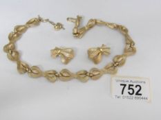 A Trifari necklace and matching earclips fashioned as a line of ribbons in gilt metal
