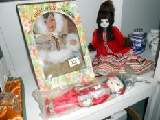 A boxed porcelain doll in American Indian costume and 2 other costume dolls