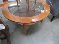 A circular teak coffee table with glass top