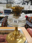 A Victorian oil lamp with glass font and brass base