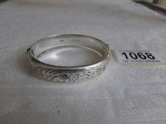 A silver engraved bangle with safety chain