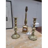 A brass lamp base and a pair of brass candlesticks