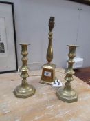 A brass lamp base and a pair of brass candlesticks