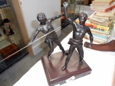 A spelter figure group on wooden base of two Grecian javelin throwers,