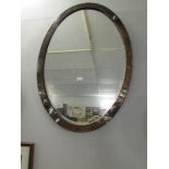 An arts and crafts copper framed oval bevel edged mirror