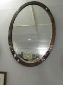 An arts and crafts copper framed oval bevel edged mirror