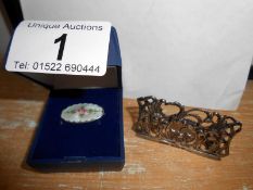 A silver place card holder and a silver and enamel brooch