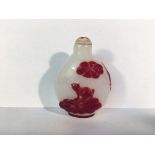 A circa 19/20th century red overlay carved glass snuff bottle depicting 2 carp swimming under a