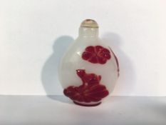 A circa 19/20th century red overlay carved glass snuff bottle depicting 2 carp swimming under a