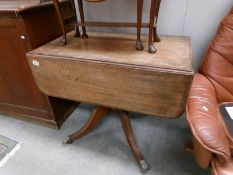 A mahogany Pembroke table with centre pedestal and on brass lions paw feet