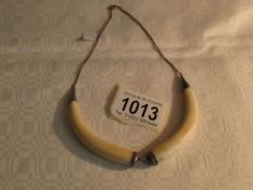 An ivory tusk necklace with white metal mounts