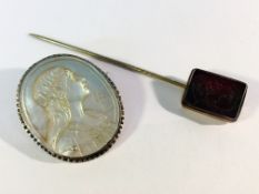 A carved mother of pearl cameo of a young girl and a carved black stone stick pin