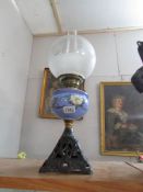 A Victorian oil lamp on cast base with hand painted font and later shade