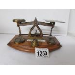 A set of 1900's brass postal scales mounted on a wood base and with set of 5 brass weights