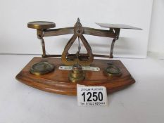 A set of 1900's brass postal scales mounted on a wood base and with set of 5 brass weights