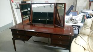 A dark wood stained triple mirrored dressing table