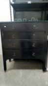 A 4 drawer black chest of drawers with glass top