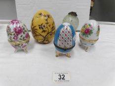 A hand decorated ceramic egg together with 3 egg shaped trinket pots and a glass hanging egg