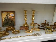 A shelf of brass including candlesticks