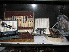 A mixed lot of cutlery sets, one shelf