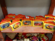 A collection of 13 Rupert the Bear die-cast cars and models in boxes