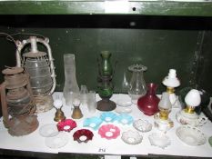 A mixed lot of lamp parts, storm lanterns etc, one shelf