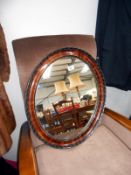 An oval wood framed wall mirror