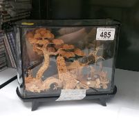 A glass case with wooden Chinese model landscape