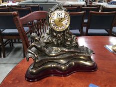 A decorative mantel clock featuring a reclining lady