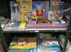 2 shelves of Rupert the Bear memorabilia including games, puzzles, puppet, clock etc.