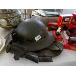 A civil defence grey Zukerman helmet marked 'L' with inner liner and a leather bandoleer belt