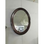 An oval framed bevel edged mirror