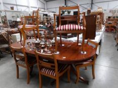 An oval extending dining table and a set of 6 brass inlaid chairs