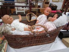 A wicker Moses basket and a quantity of old dolls