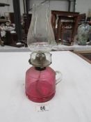 A cranberry glass hand oil lamp with chimney