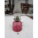 A cranberry glass hand oil lamp with chimney