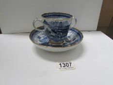 An early 19th century soft paste blue and white loving cup an saucer with gilt edging