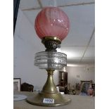 A Victorian oil lamp with glass font and etched cranberry glass shade