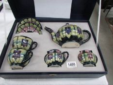 A cased Moorcroft 'Violet' breakfast comprising teapot, milk jug, sugar bowl,