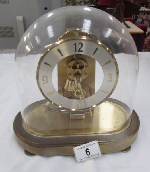 A brass clock under acrylic dome