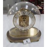 A brass clock under acrylic dome