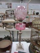 A Victorian silver plated oil lamp with cranberry glass font and shade